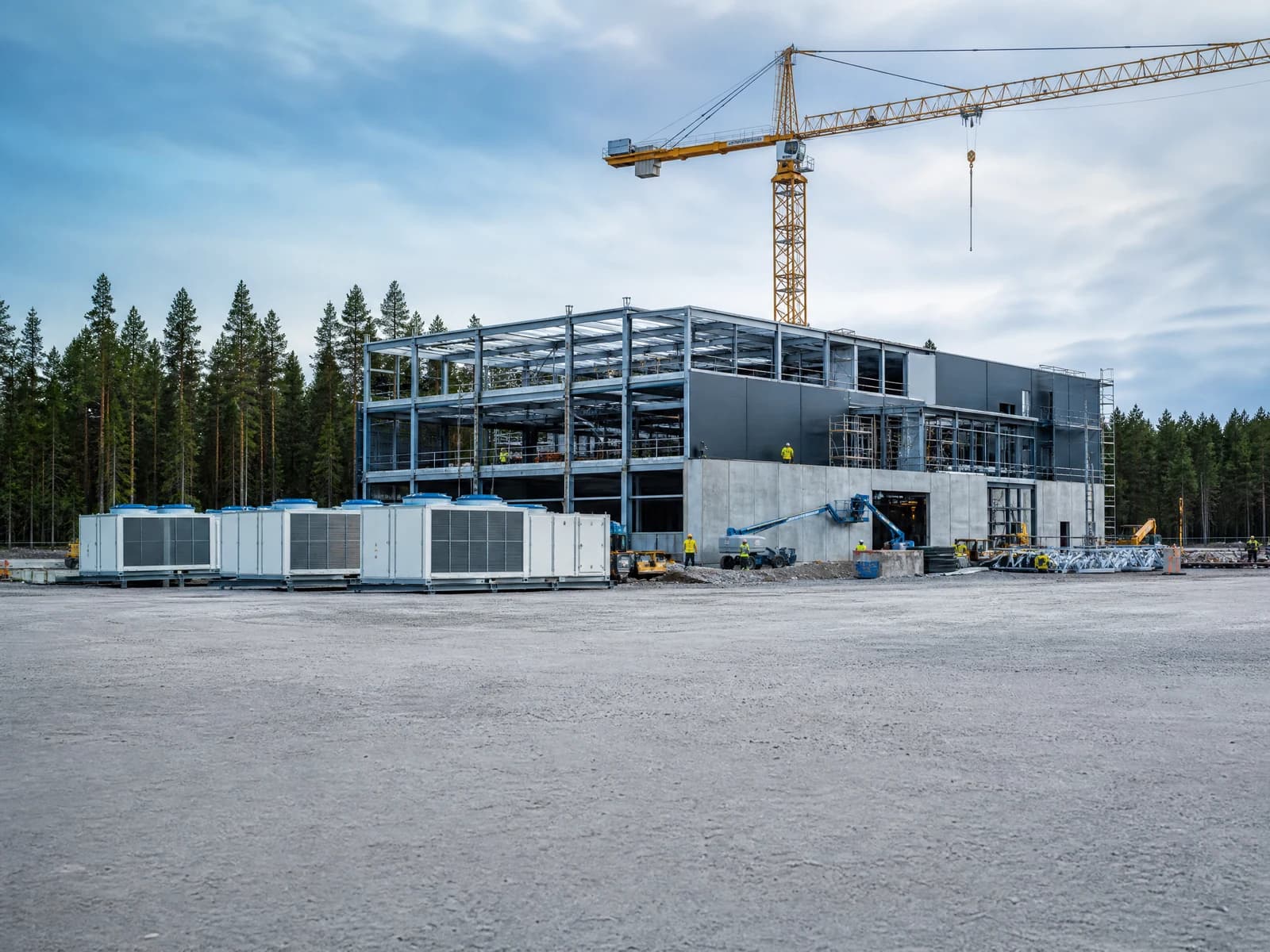 A data center build in a Swedish forest setting, cladding going on and cooling plant waiting to be lifted